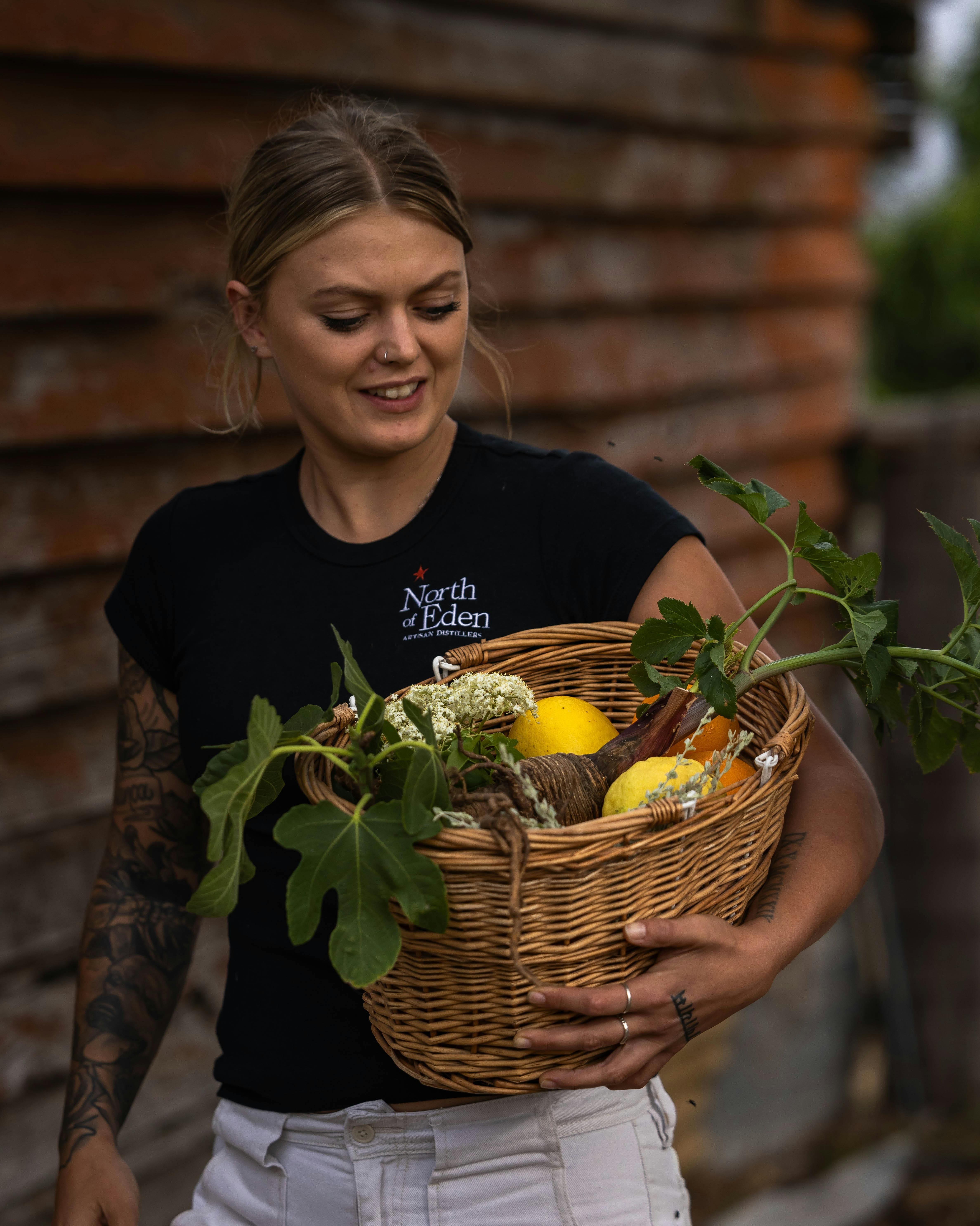 Young woman holding basket of various flowers and fruit