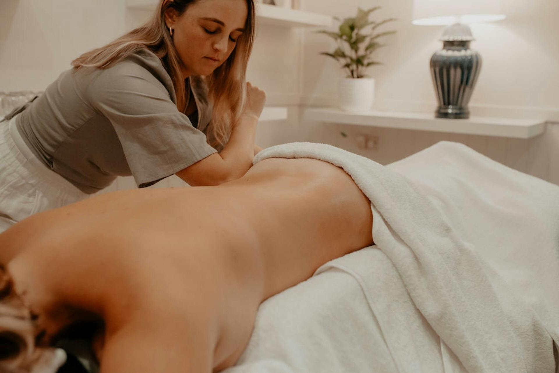 Massage Therapist Massages a person laying facedown on a massage table