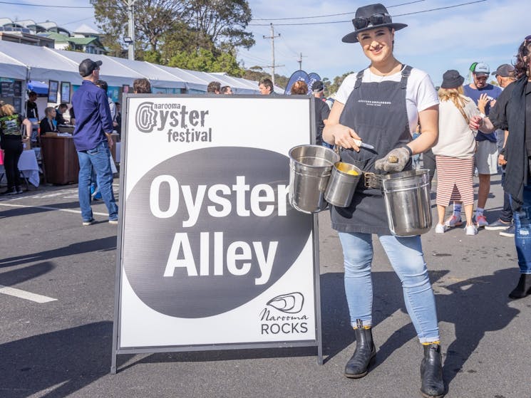 A girl wearing a shucking belt stands at the entrance to Oyster Farmers Alley