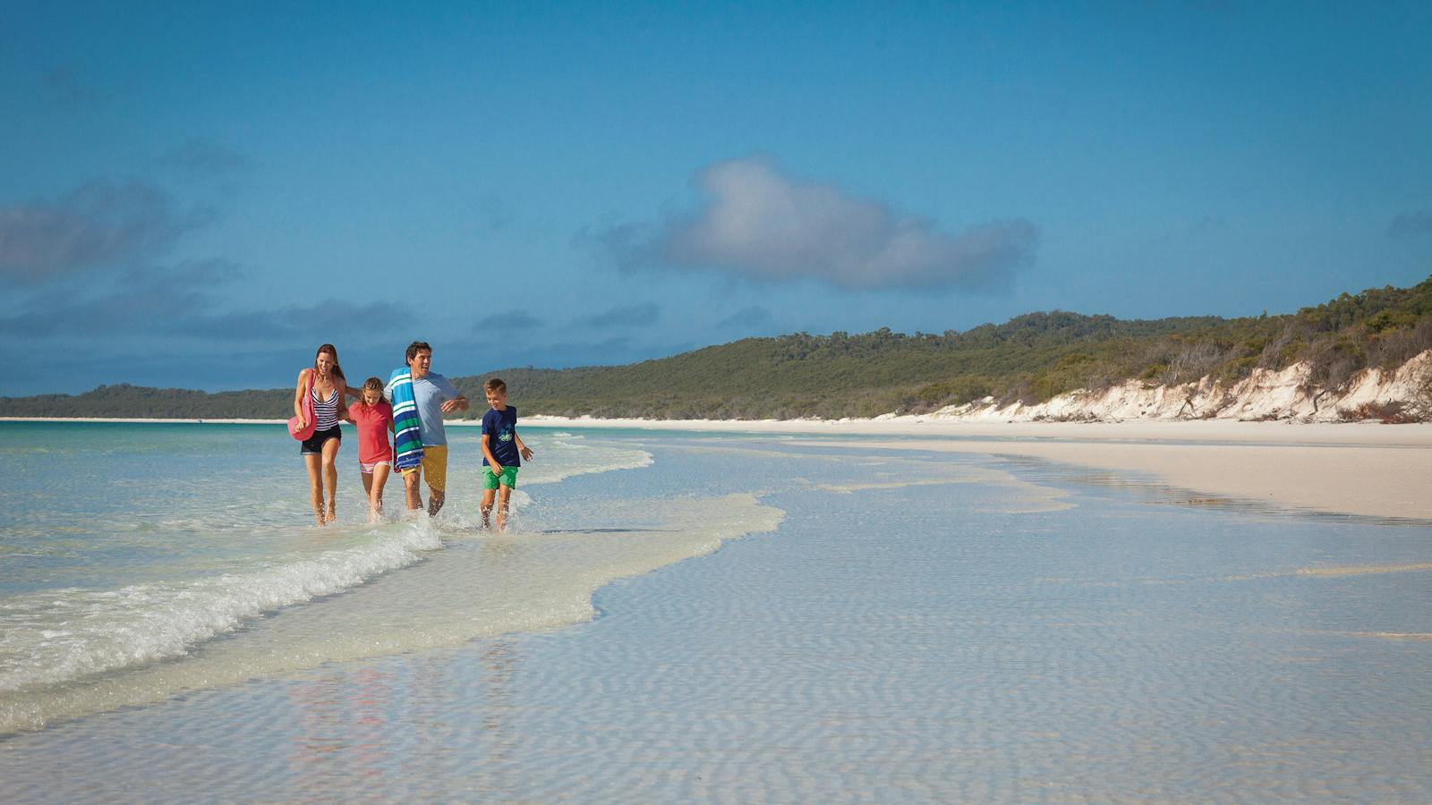 Family walking in shallows on Whitehaven Beach.