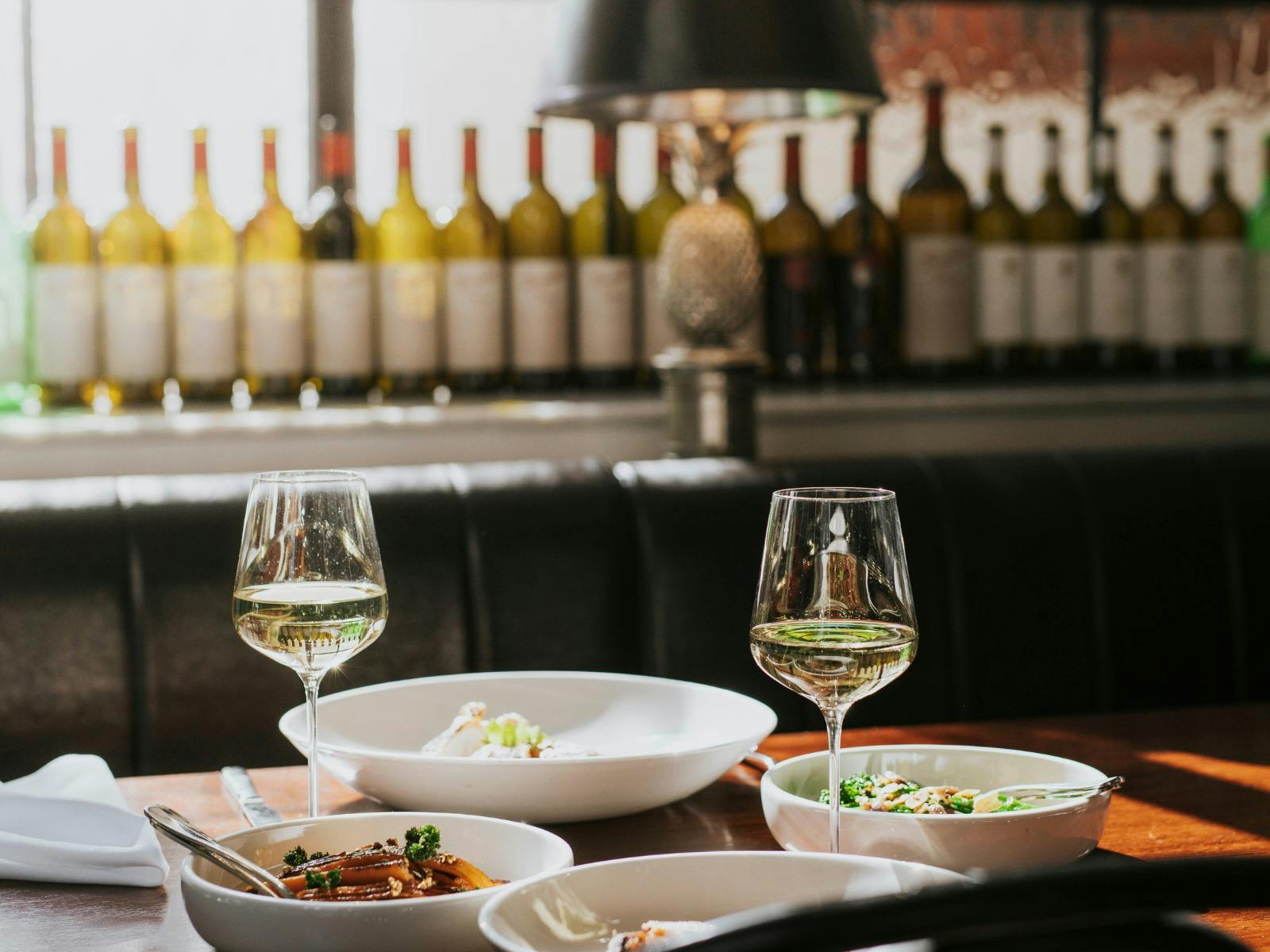 A dining table at The Heritage set for two - with glasses of wine poured and plates of food served