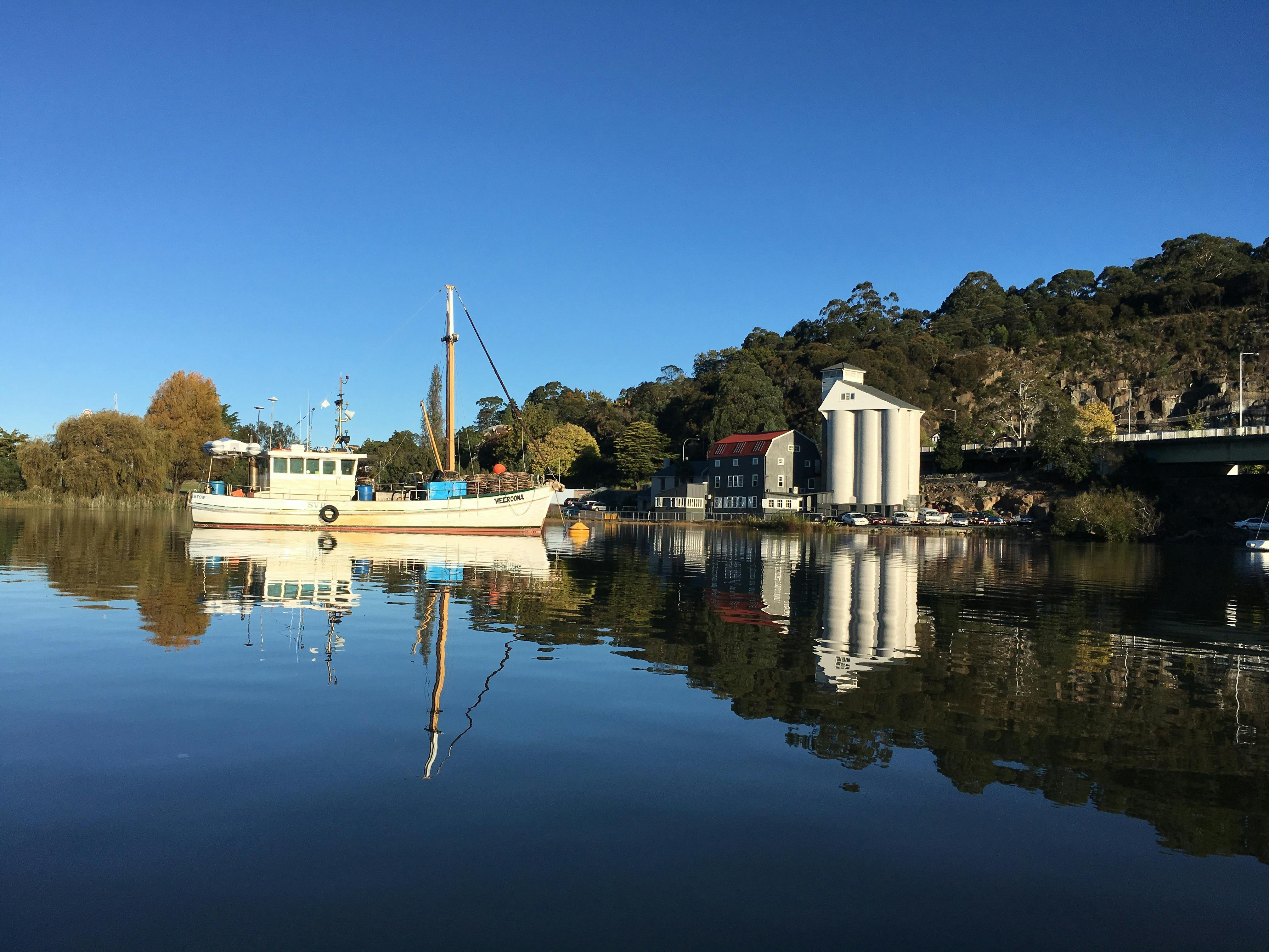 A fishing boat and building reflected in still water of the Tamar River