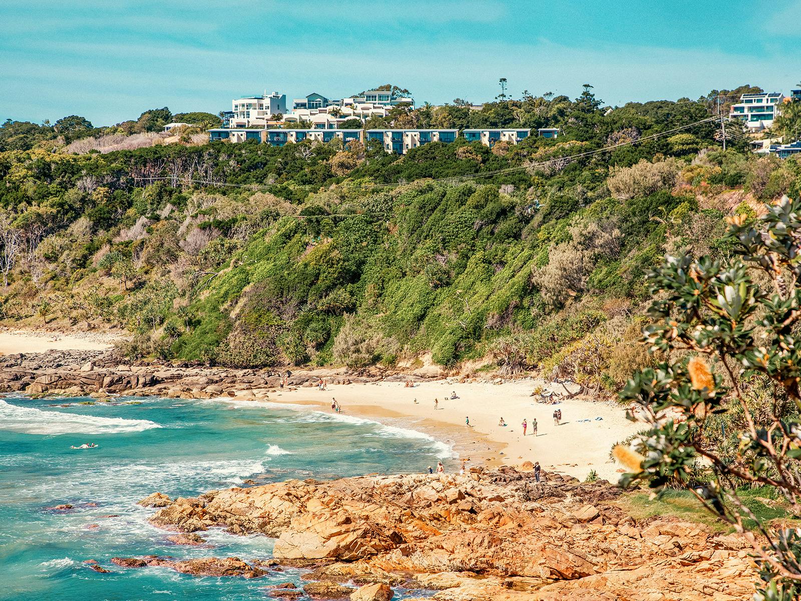 High angle of First Bay, Coolum Beach with swimmers enjoying clear blue water.