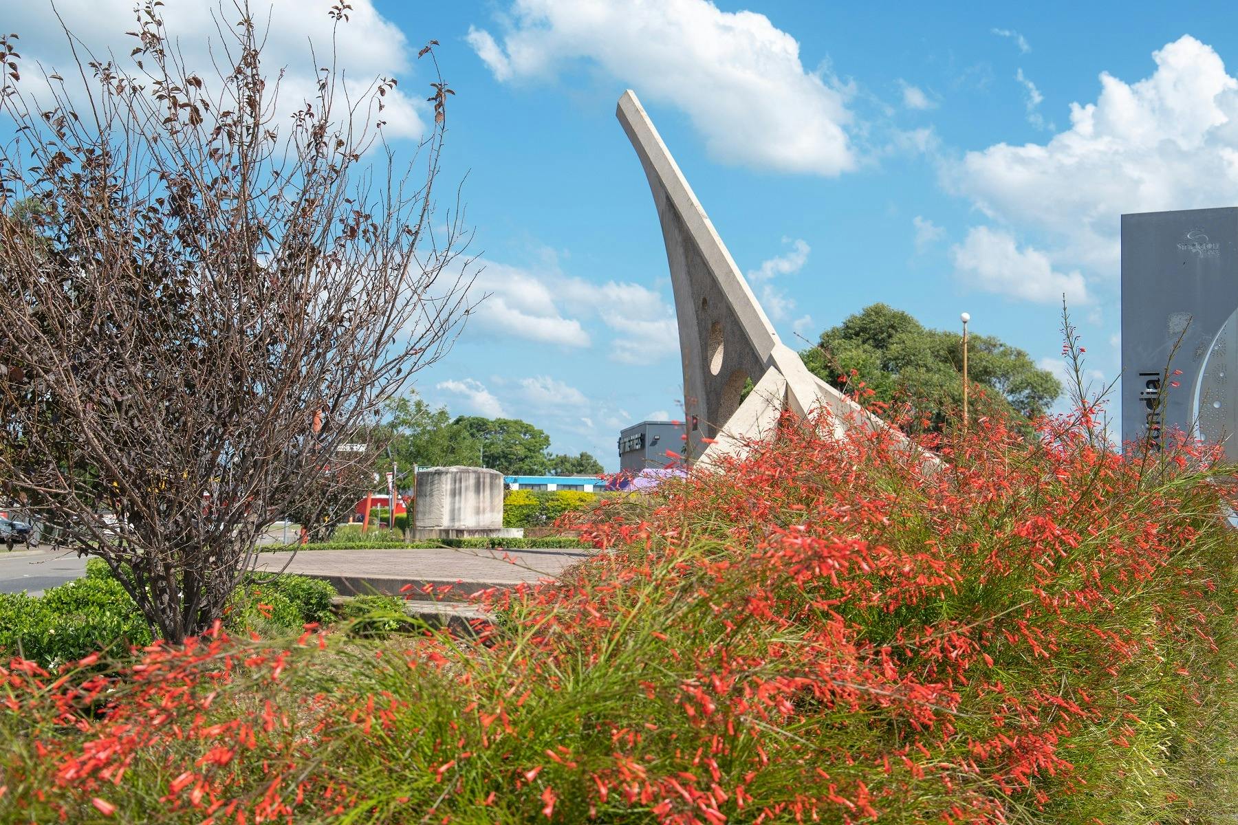 Singleton Sundial as seen through flowering plants in Rose Point Park.