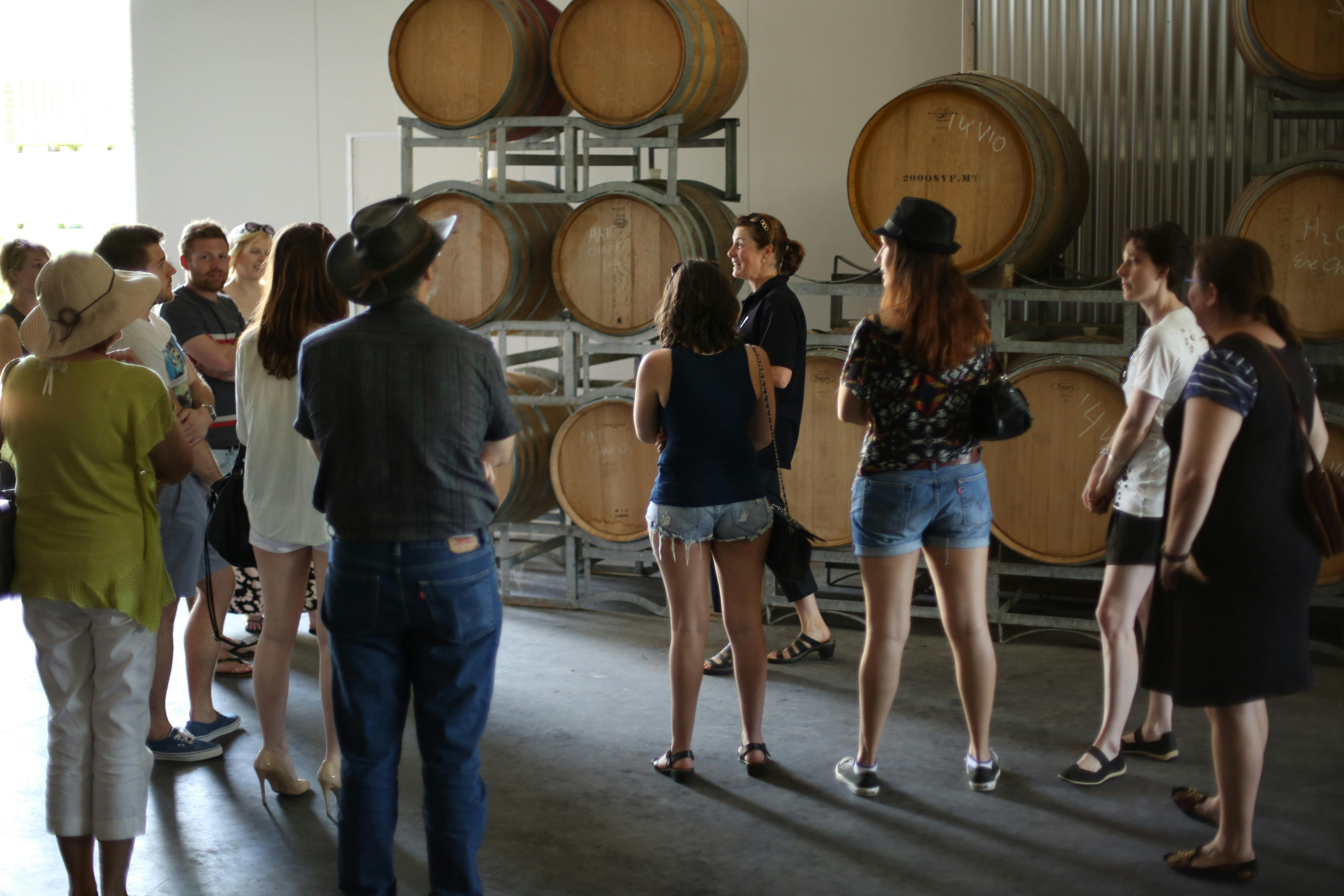 Wine barrels and tour group with owner touring the winery.