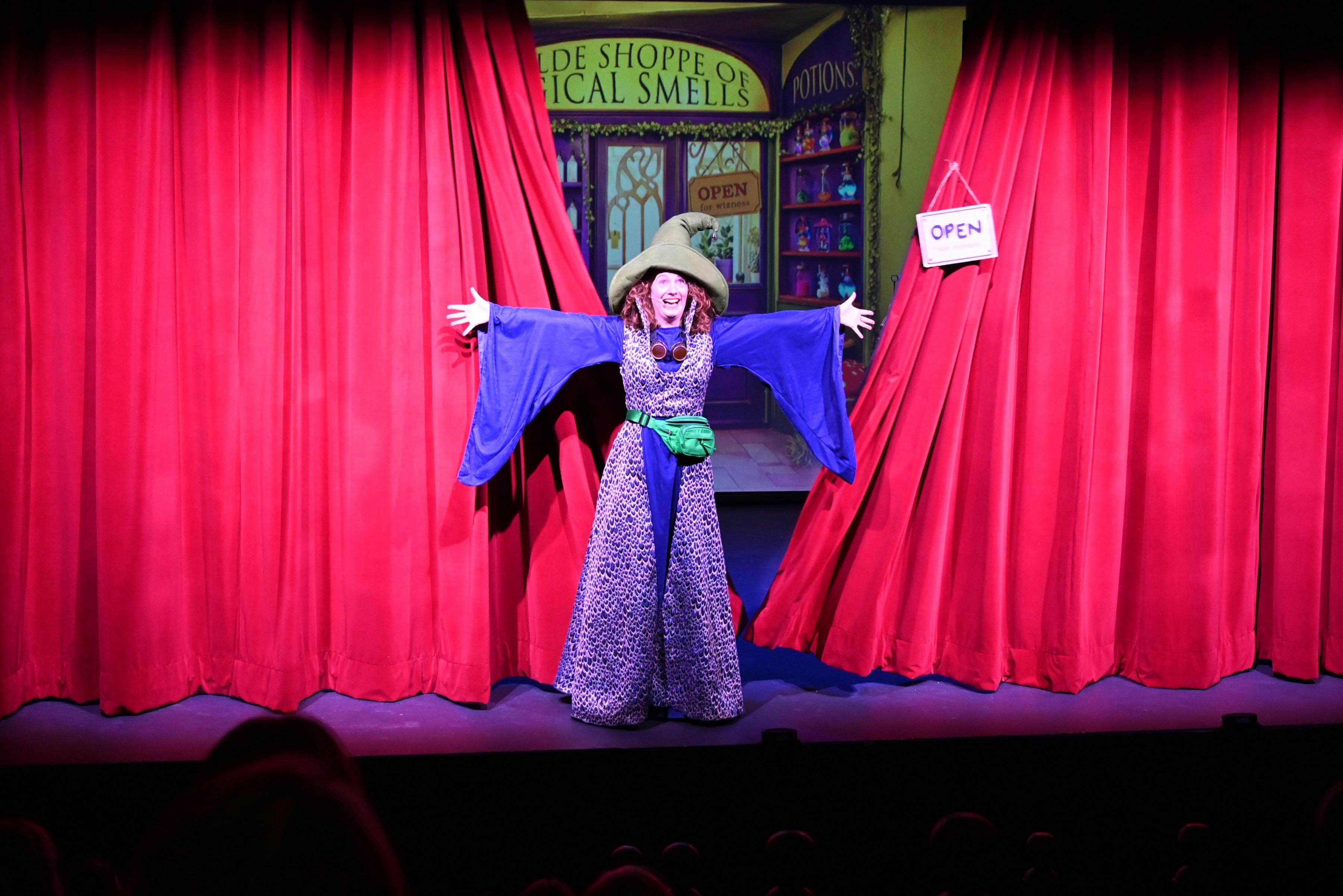 Wizard standing infront of red curtain as it opens
