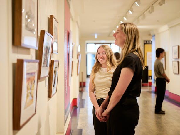 Two women view artwork in gallery.
