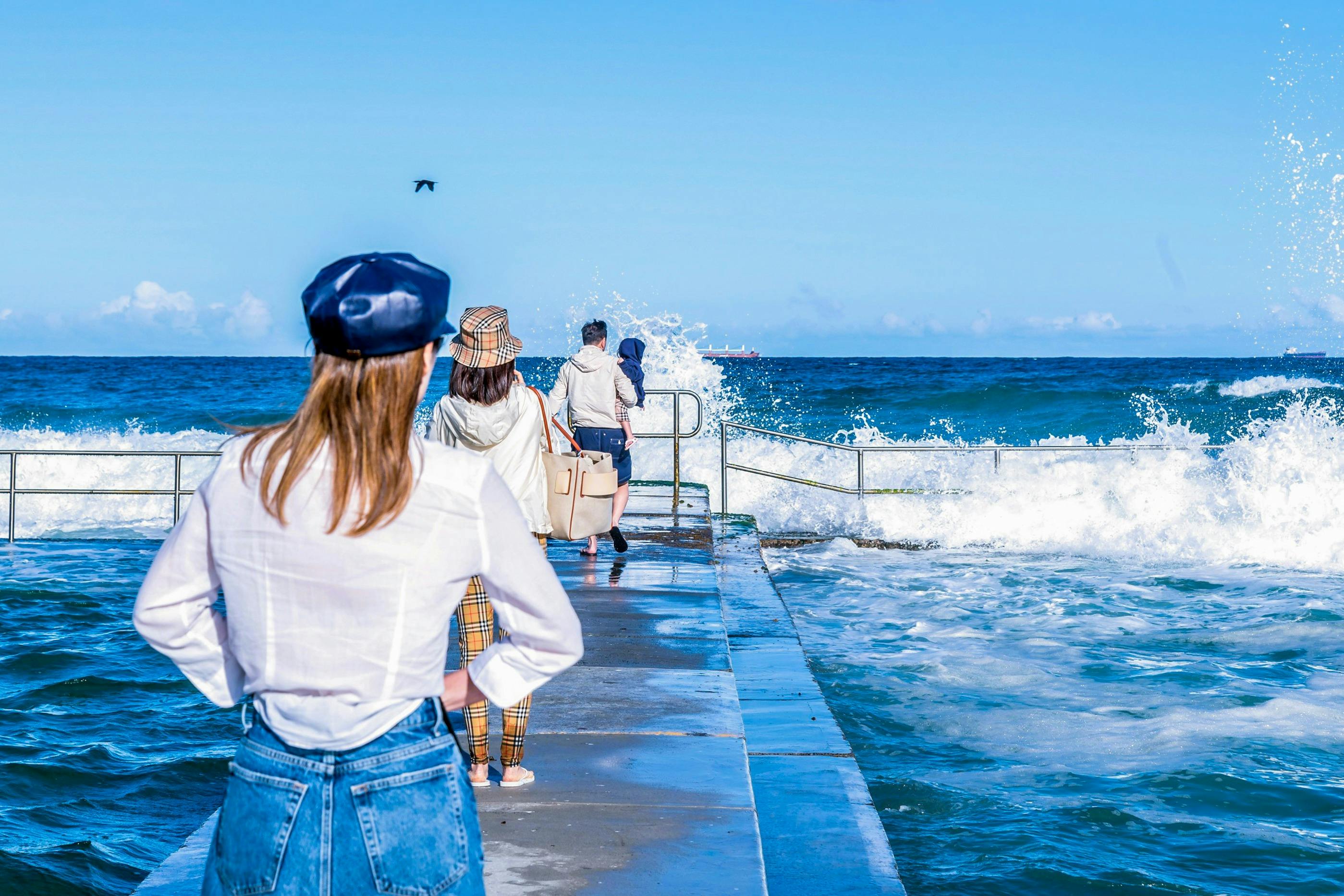 People walk on a concrete platform between two rock pools
