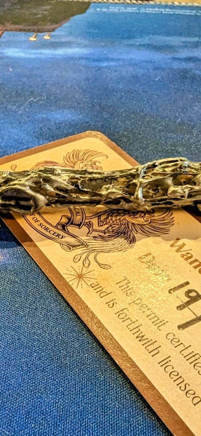 Photo of a handmade wand on a table with a completed wand license.