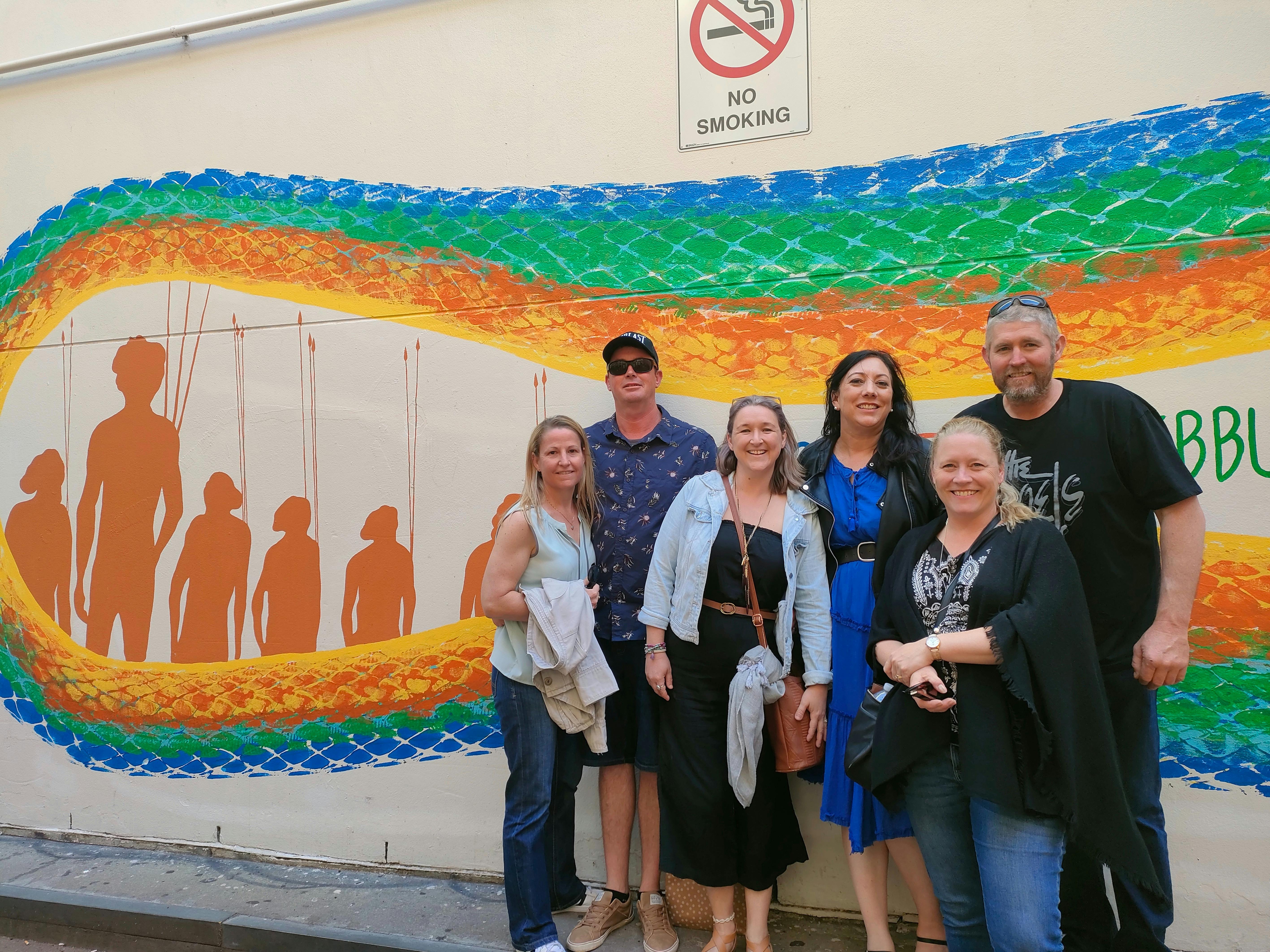A group of tour guests in front of a rainbow