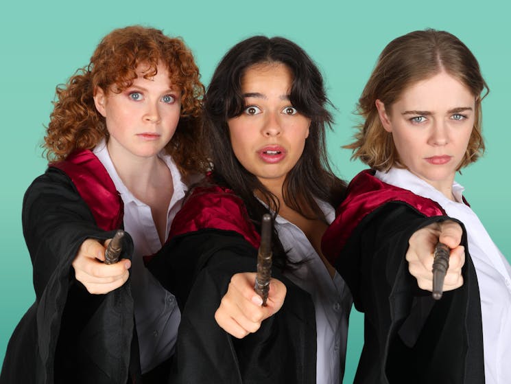 three young women dressed in harry potter style outfits with wands against a green backdrop