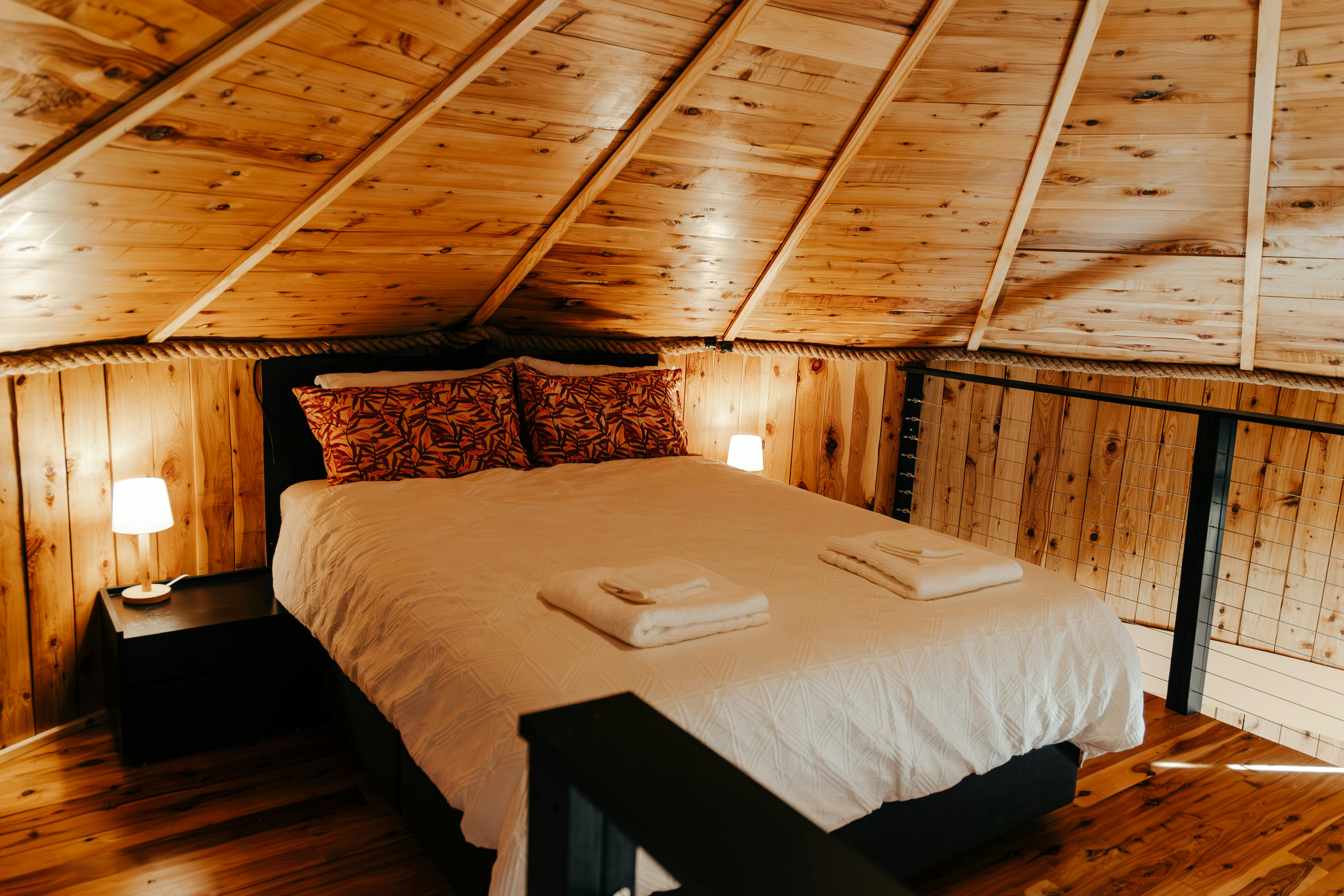 Bedroom 2  on the mezzanine level has a queen bed under a  loft style roof