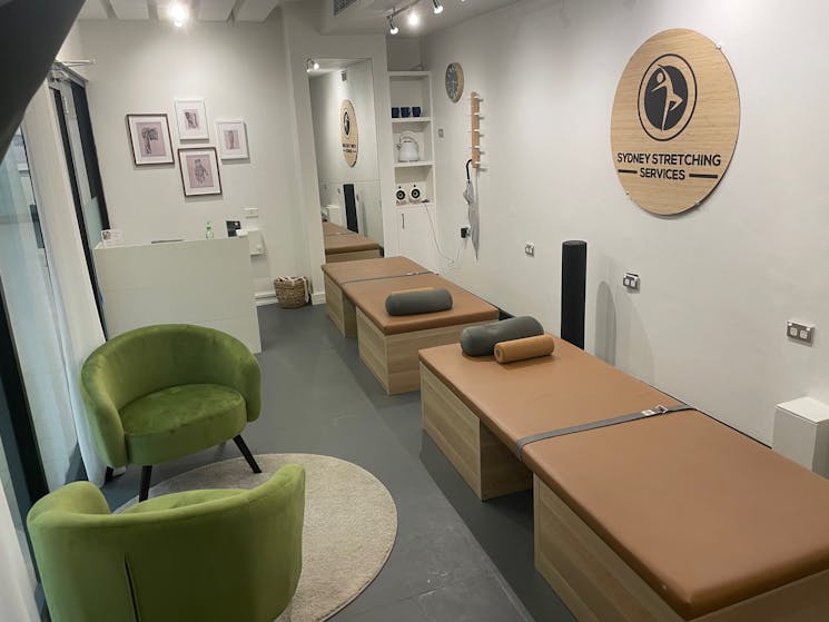 Photo shows stretch therapy beds, reception desk and seating area inside our studio.