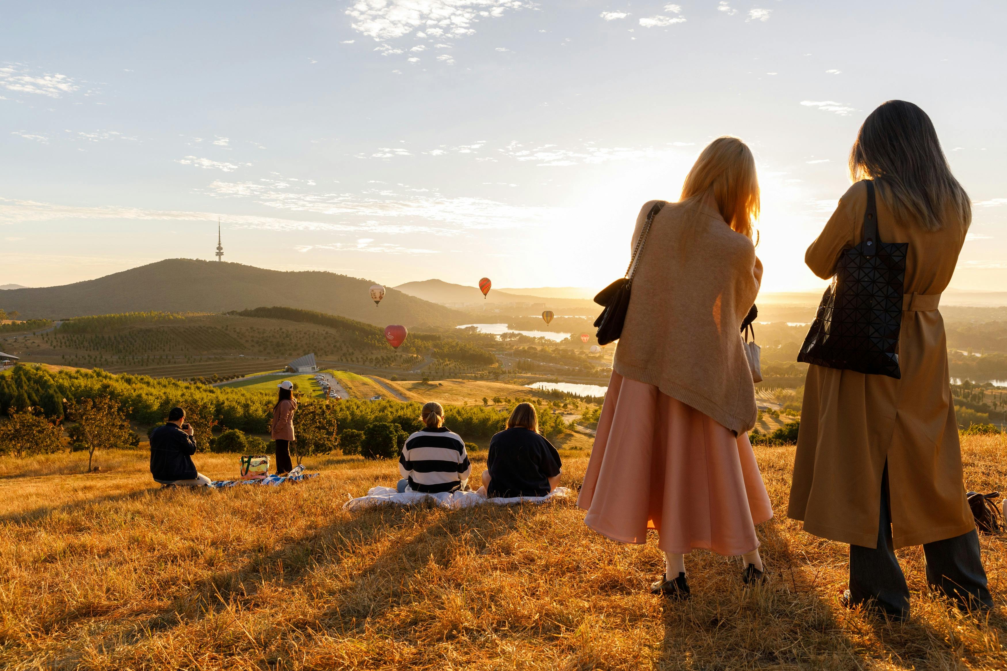 People up at lookout location to watch the balloons float over the Canberra skyline