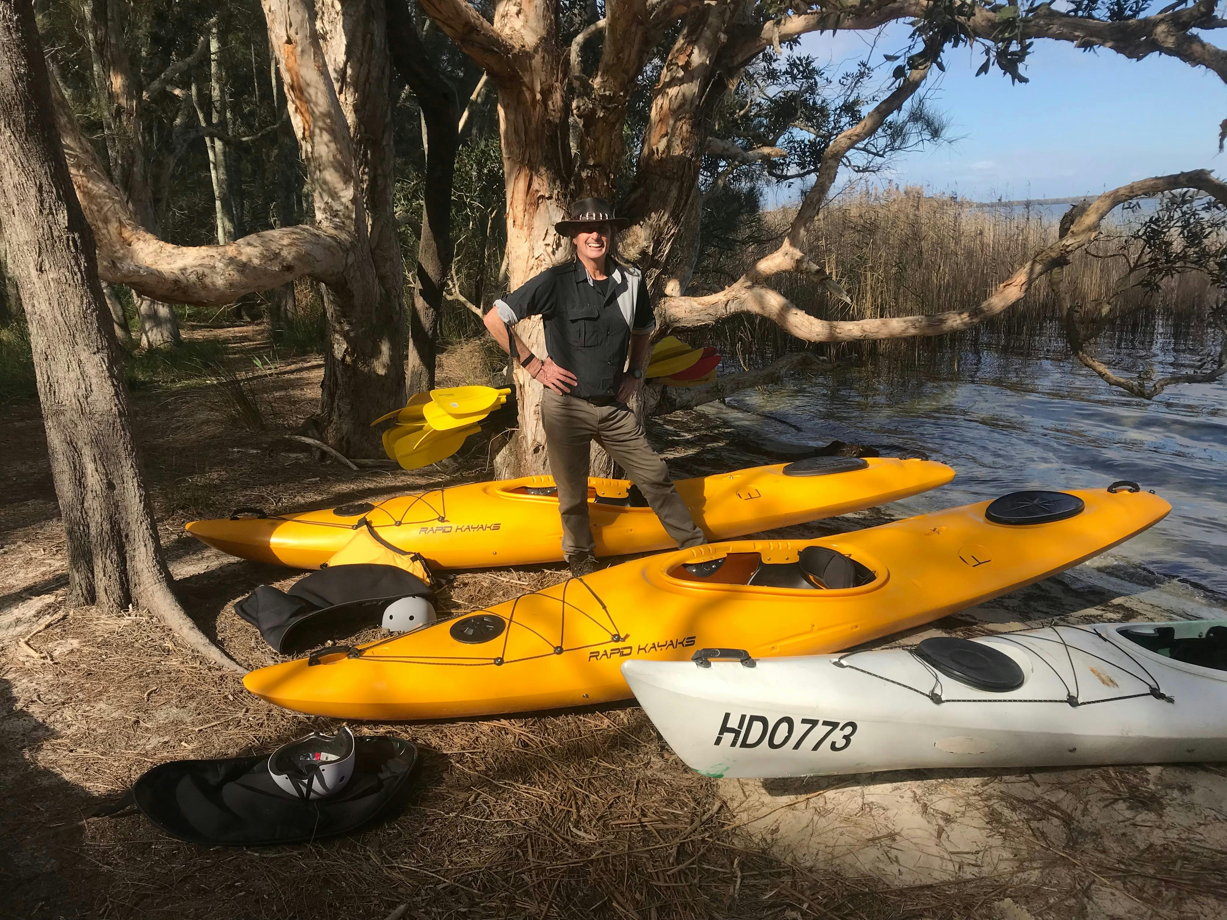 A Guide is Standing beside some Kayaks on the bank during Things to do on the Myall Lakes.