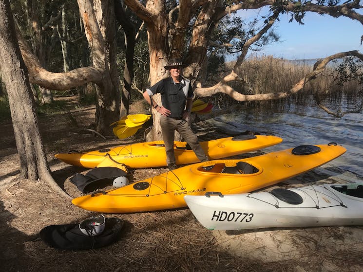 A Guide is Standing beside some Kayaks on the bank during Things to do on the Myall Lakes.