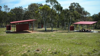 Two shelters, bathroom facility and trees in background