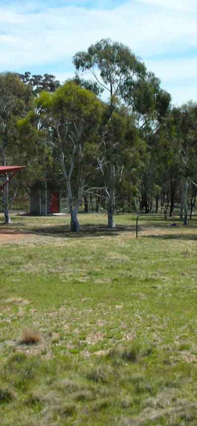 Two shelters, bathroom facility and trees in background