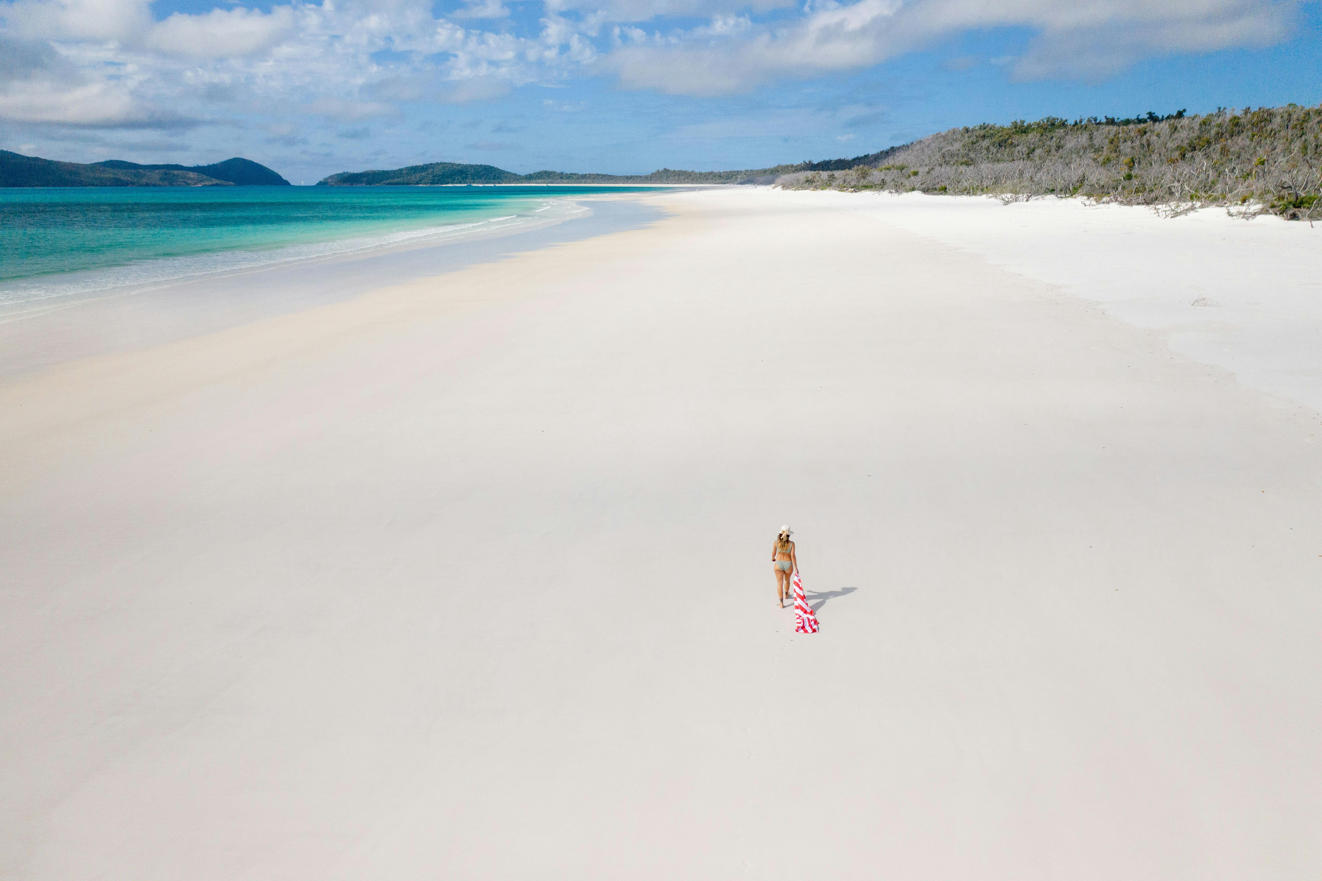 A woman strolling along the wide and long white silky beach