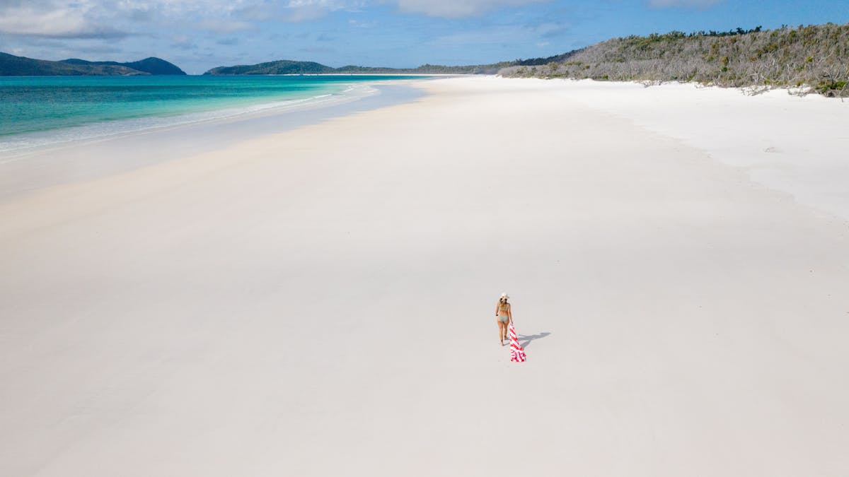 A woman strolling along the wide and long white silky beach