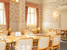 Light filled restaurant dining room with timber tables and woven chairs