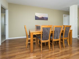 Image of timber kitchen table with seating for 8 on comfortable chairs. Timber floor