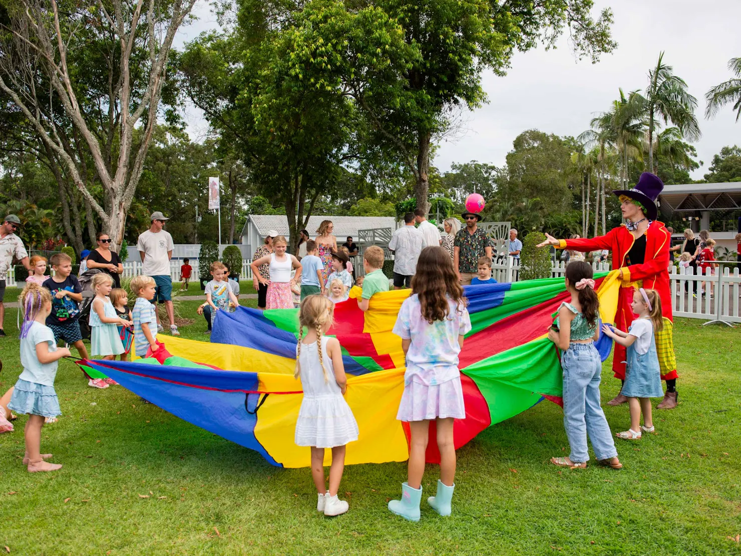 Children all holding a colourful parachute on the lawn