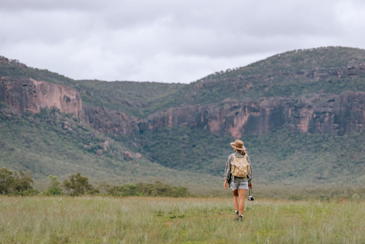 A woman hikes with a backpack, overlooking Mt Mulligan in the Mareeba Shire, North Queensland.