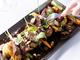 A plate of our tuscan lamb, with assorted veggies, chat potatoes, walnuts & goats cheese in  a jus