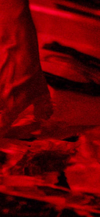 A photograph of a hand in a darkroom tray developing a photographic print