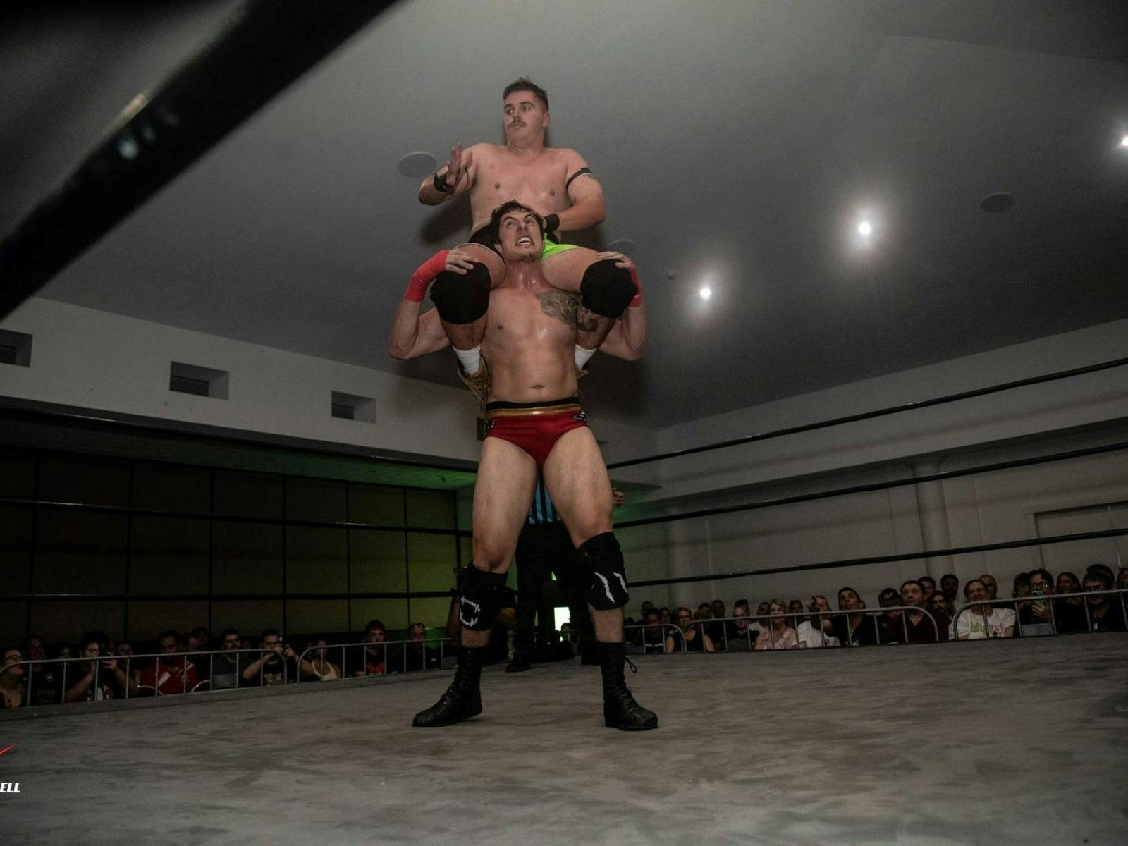 Two wrestlers, one sitting on the others shoulders