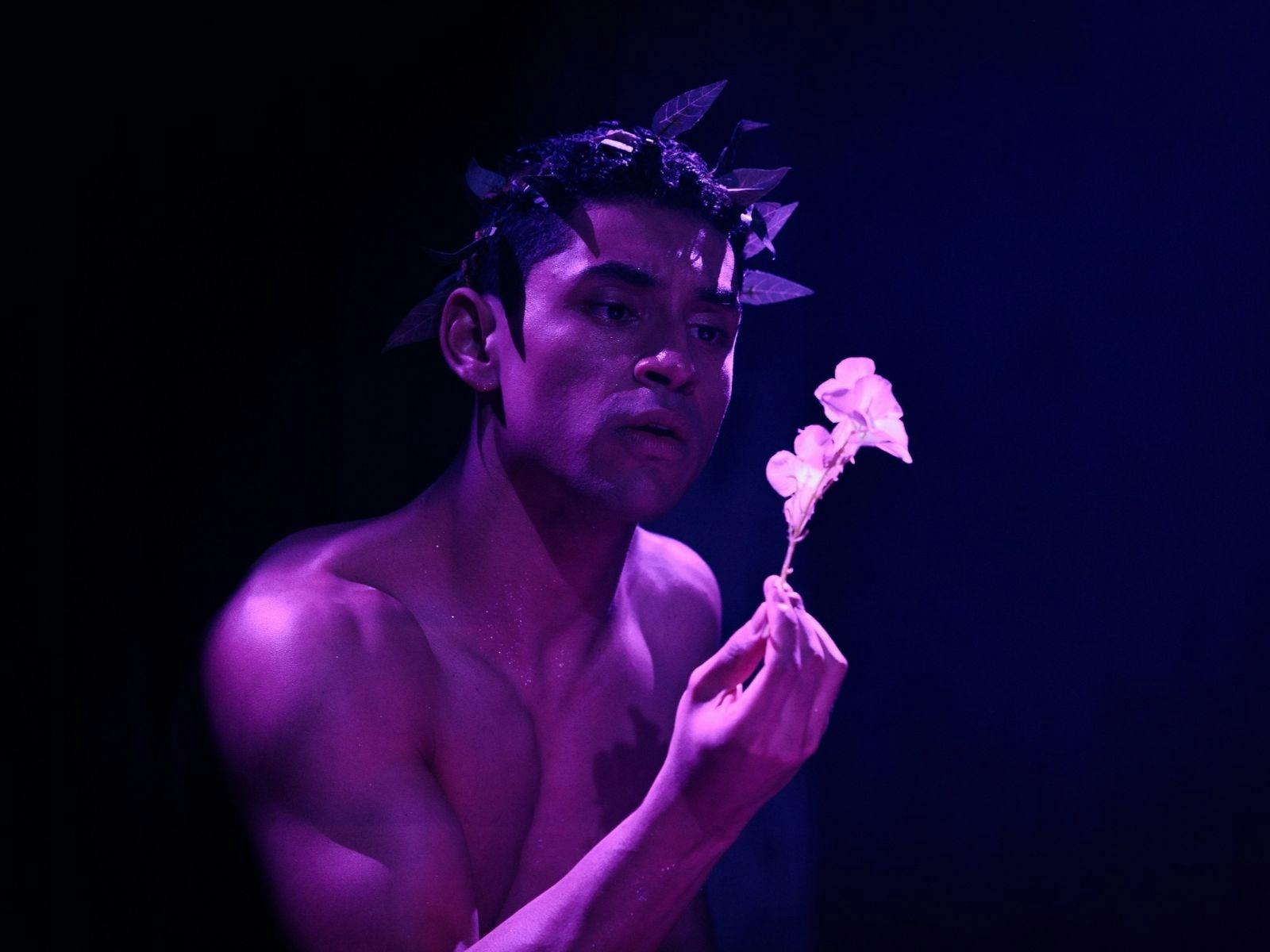 man holding a flower with no shirt on