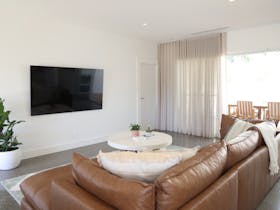 Living room with leather couch, wall mounted TV and sliding doors