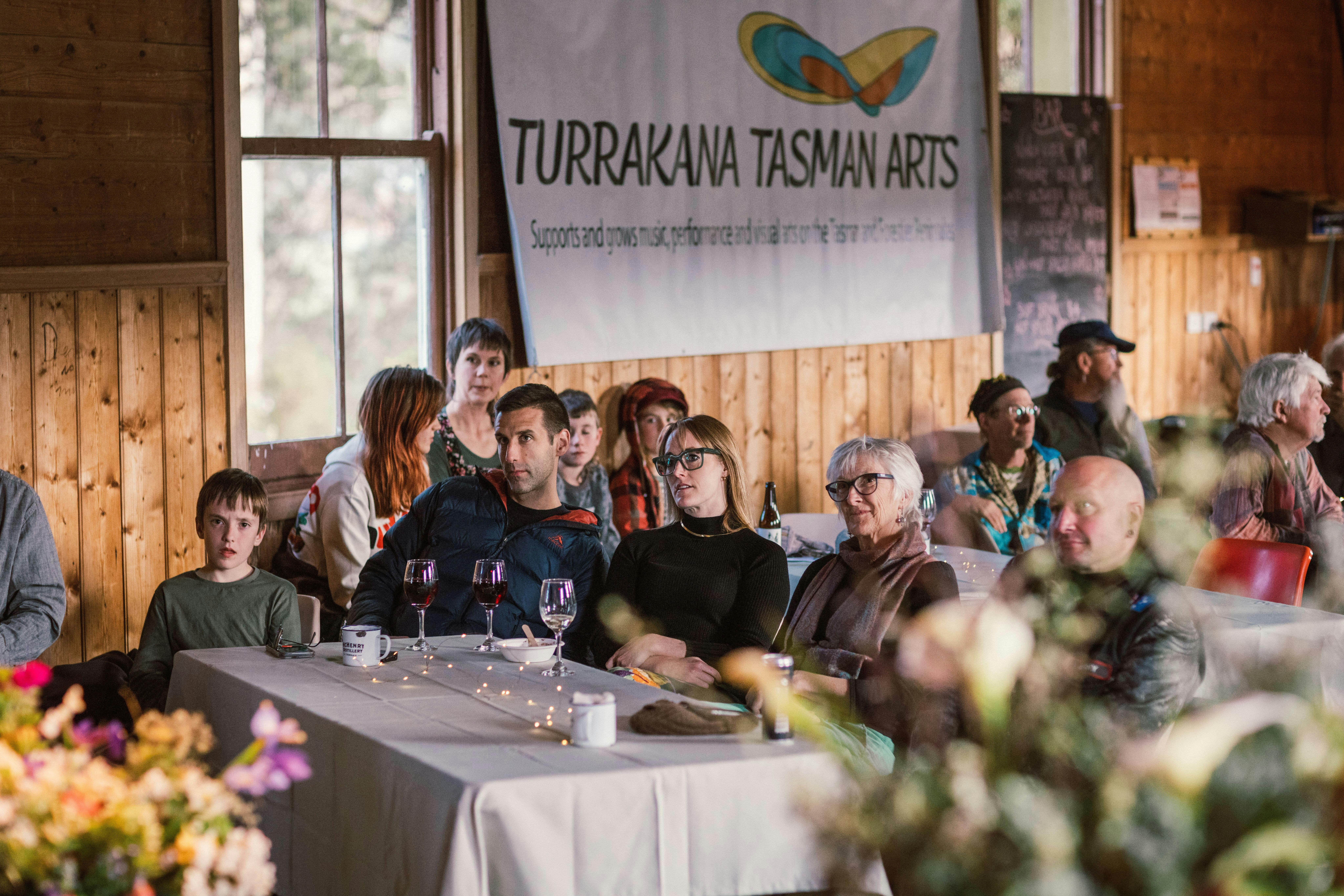 A group of people are sitting at tables inside the hall.