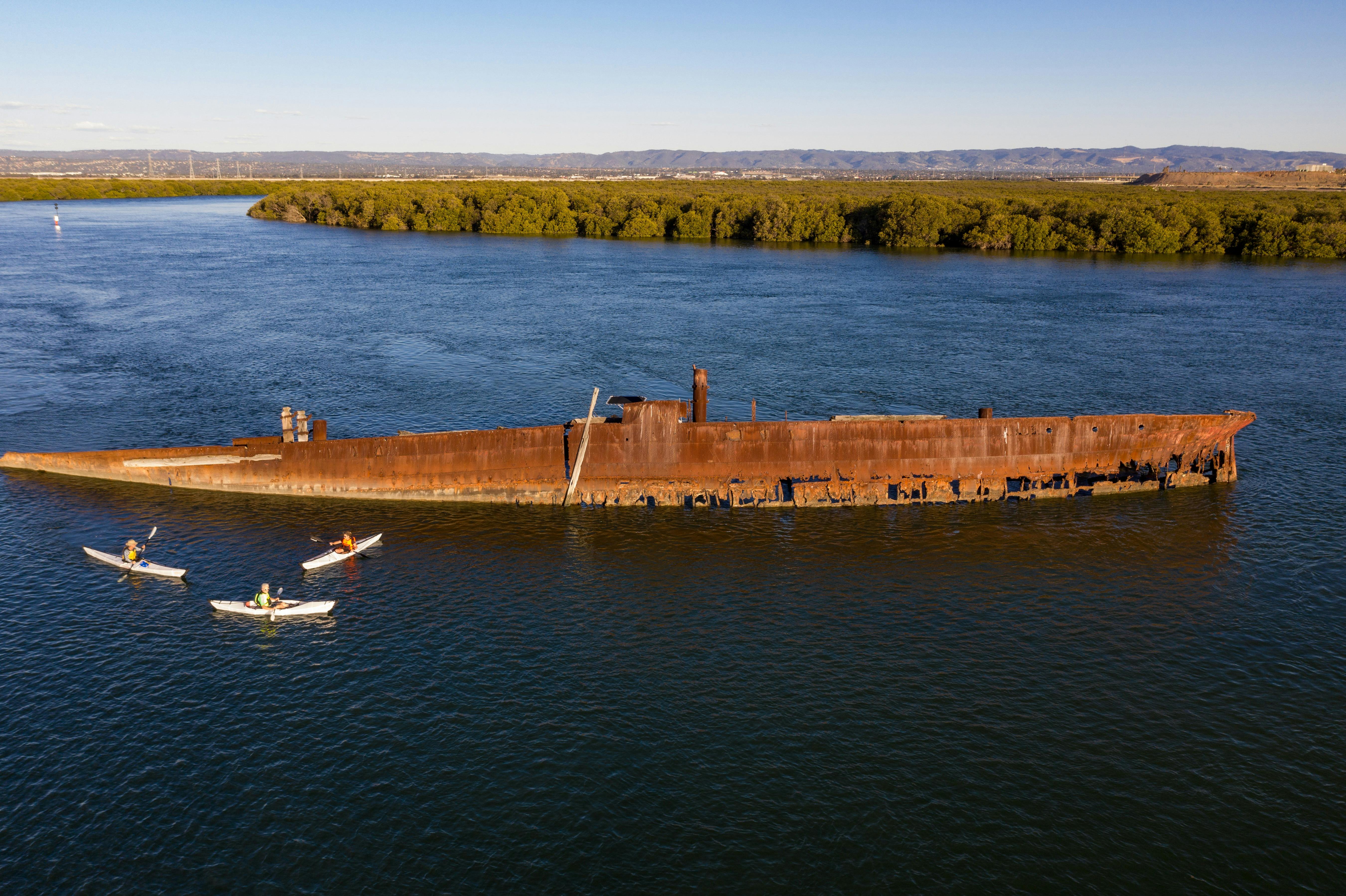 Three kaykers paddling around shipwreck Santiago