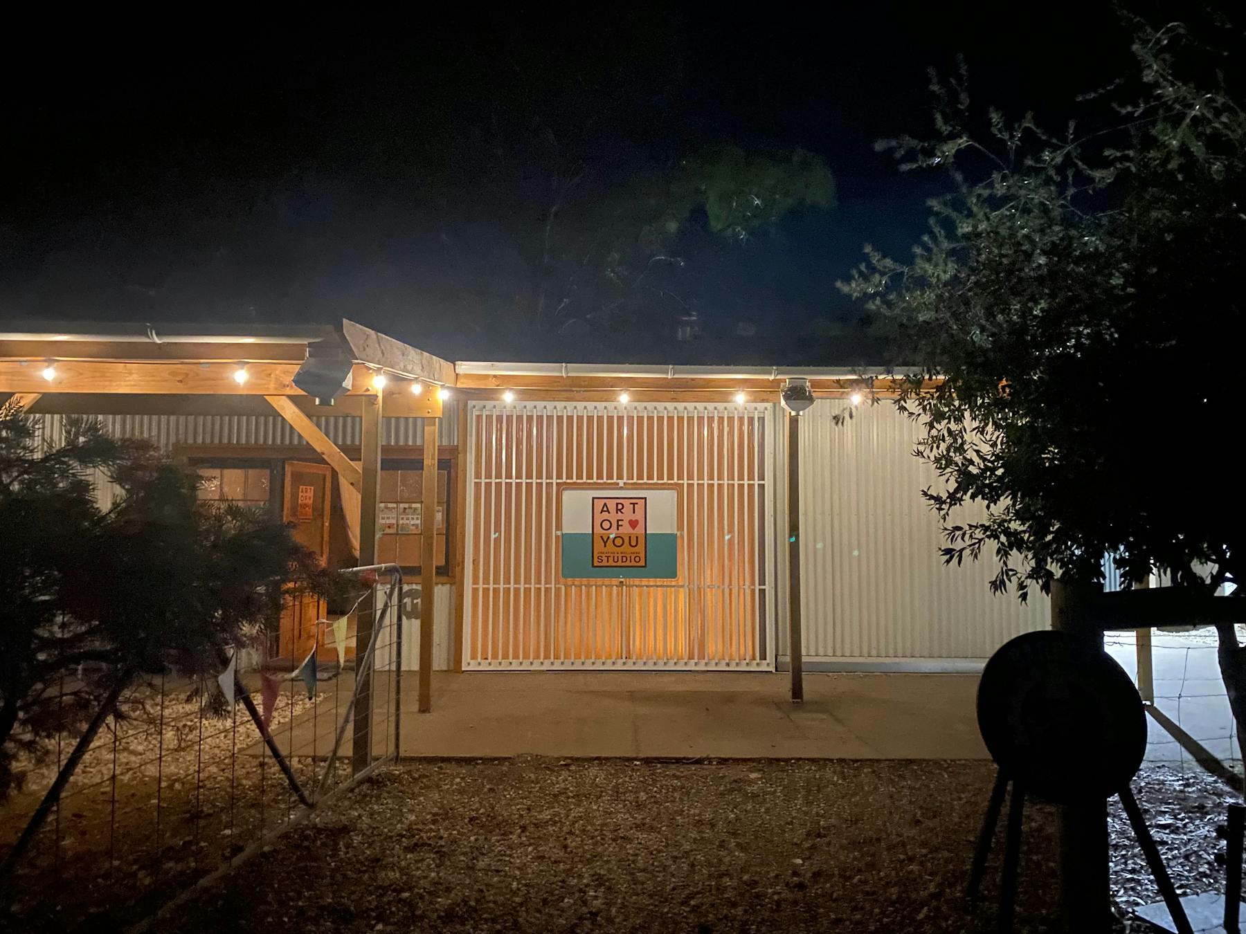 Studio entrance at night time with warm lights, and art of you sign