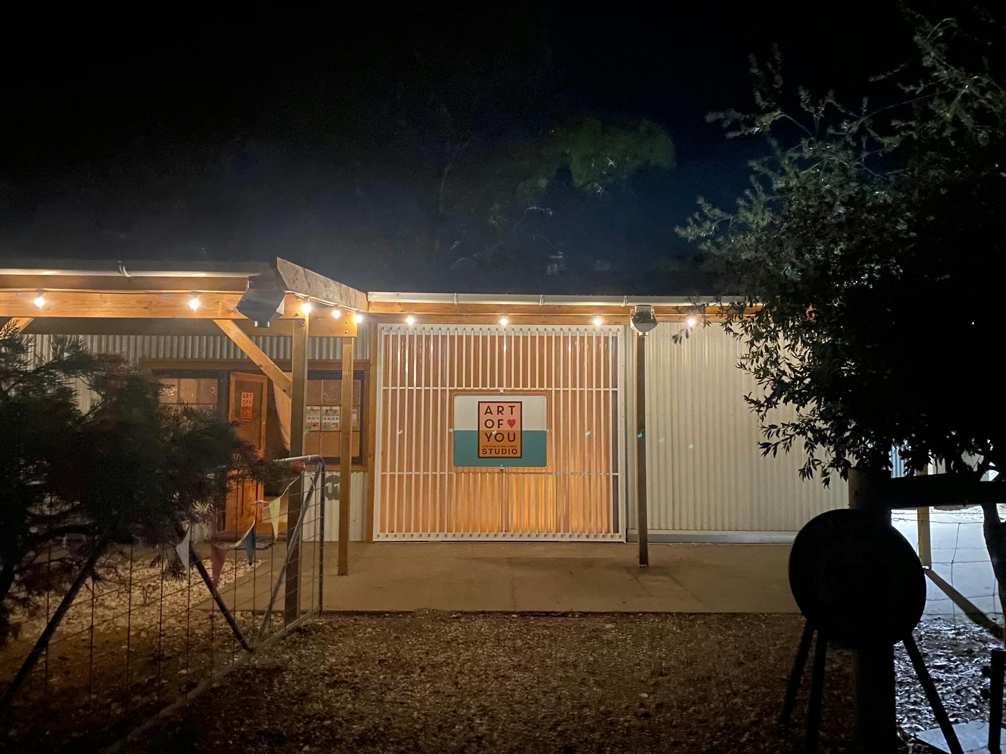 Studio entrance at night time with warm lights, and art of you sign