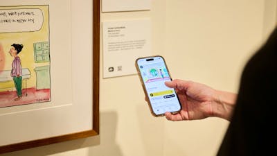Phone shows audio description of political cartoon in gallery.