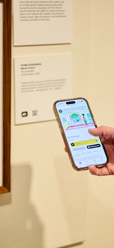 Phone shows audio description of political cartoon in gallery.