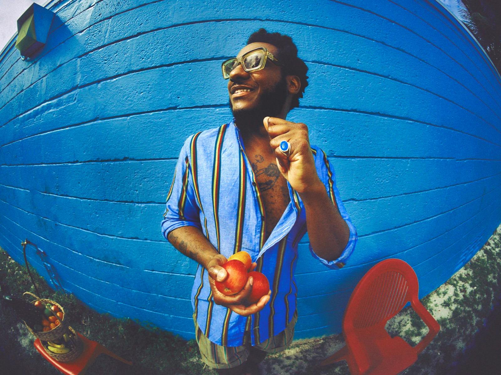 Leon Bridges dancing by a blue wall