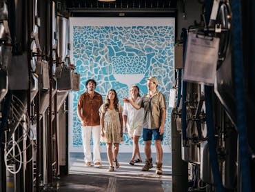group of 4 people stanidng in door way, foreground is stainless steel fermentation tanks group of 4 people stanidng in door way, foreground is stainless steel fermentation tanks