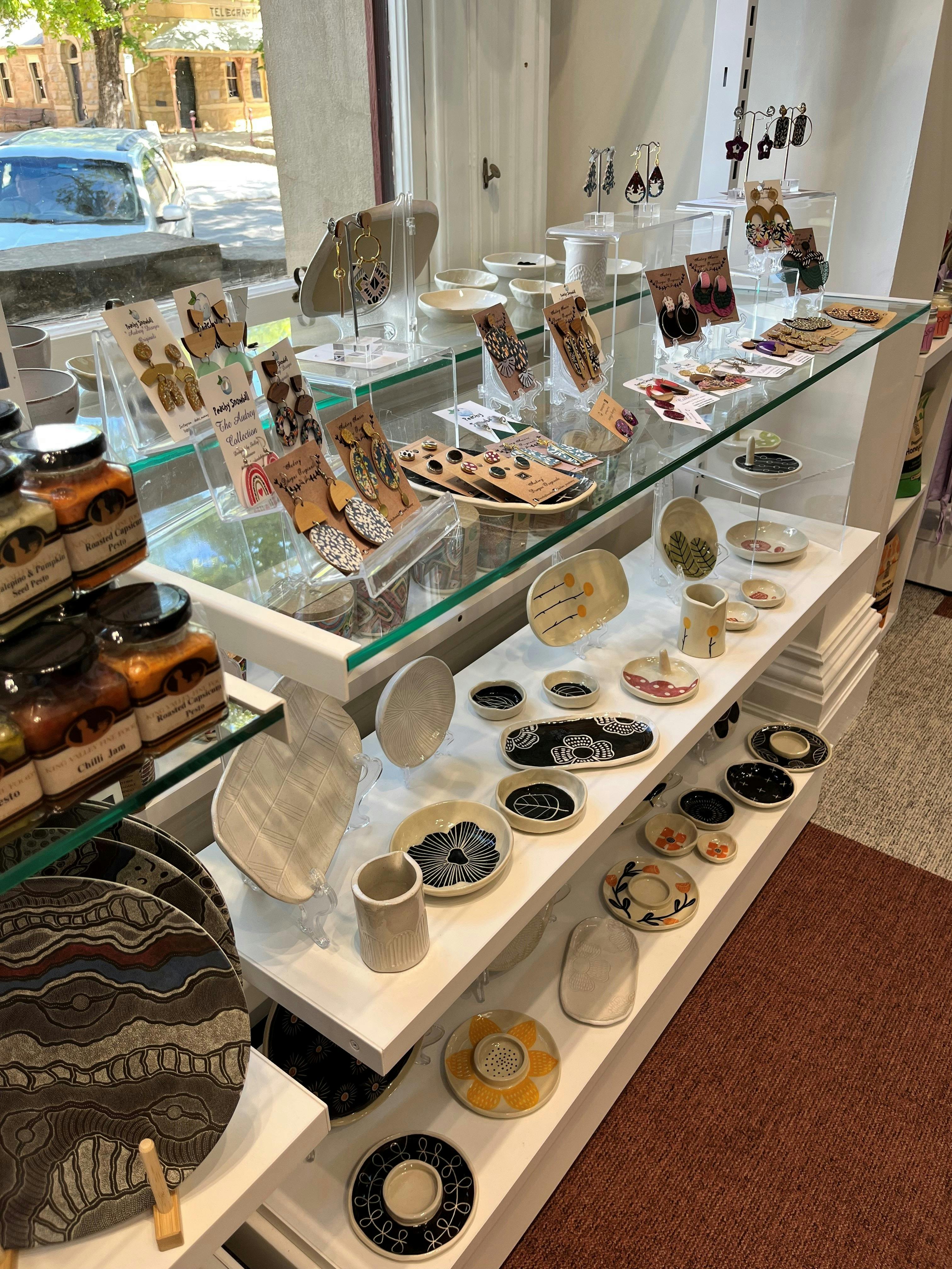 white and glass shelving displaying jewellery, ceramics and produce