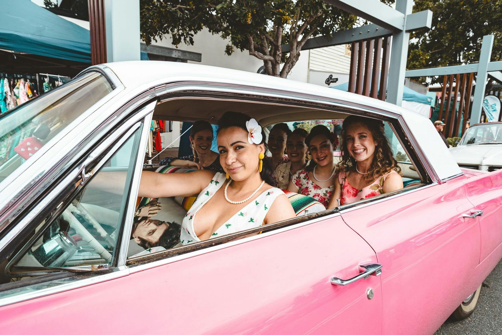 Pin Ups sitting in a pink Cadillac