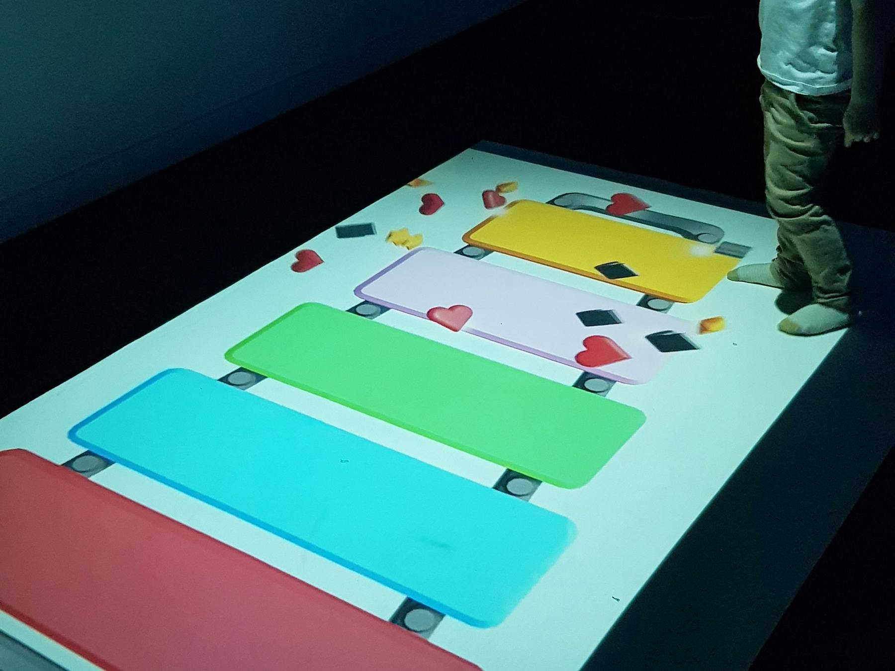 Young child moving his body to interact with a large-format digital game projected onto a floor.