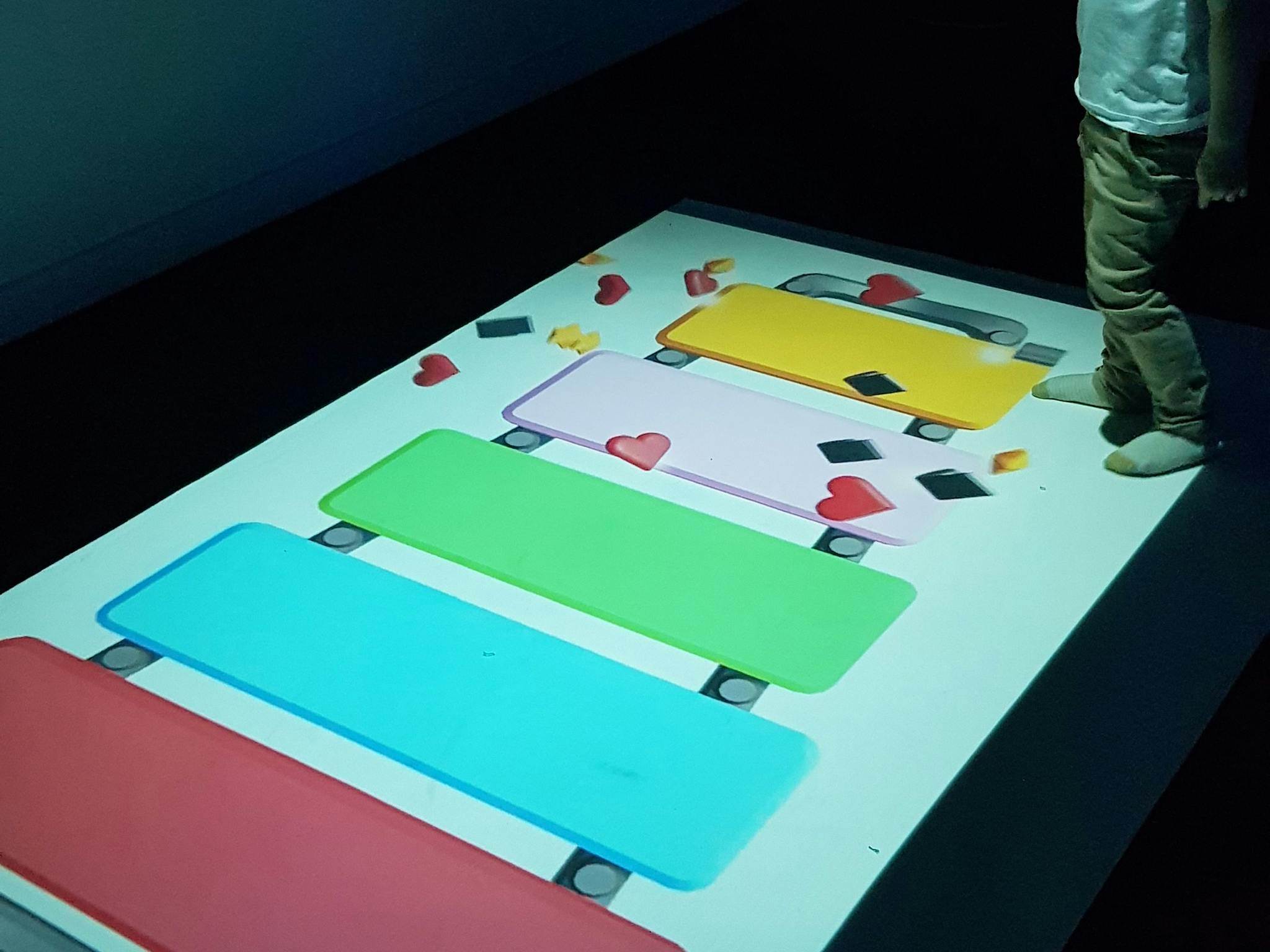 Young child moving his body to interact with a large-format digital game projected onto a floor.