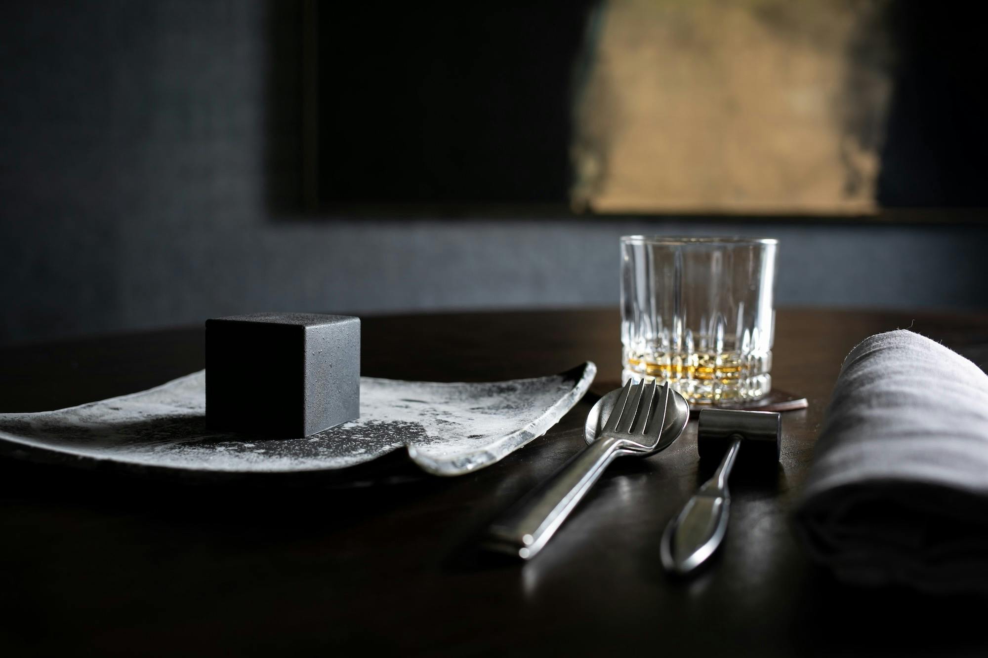 An image of a small black box with cutlery either side including a hammer to smash the dessert box