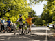 A group of riders wheel their mountain bikes through a historic street scape