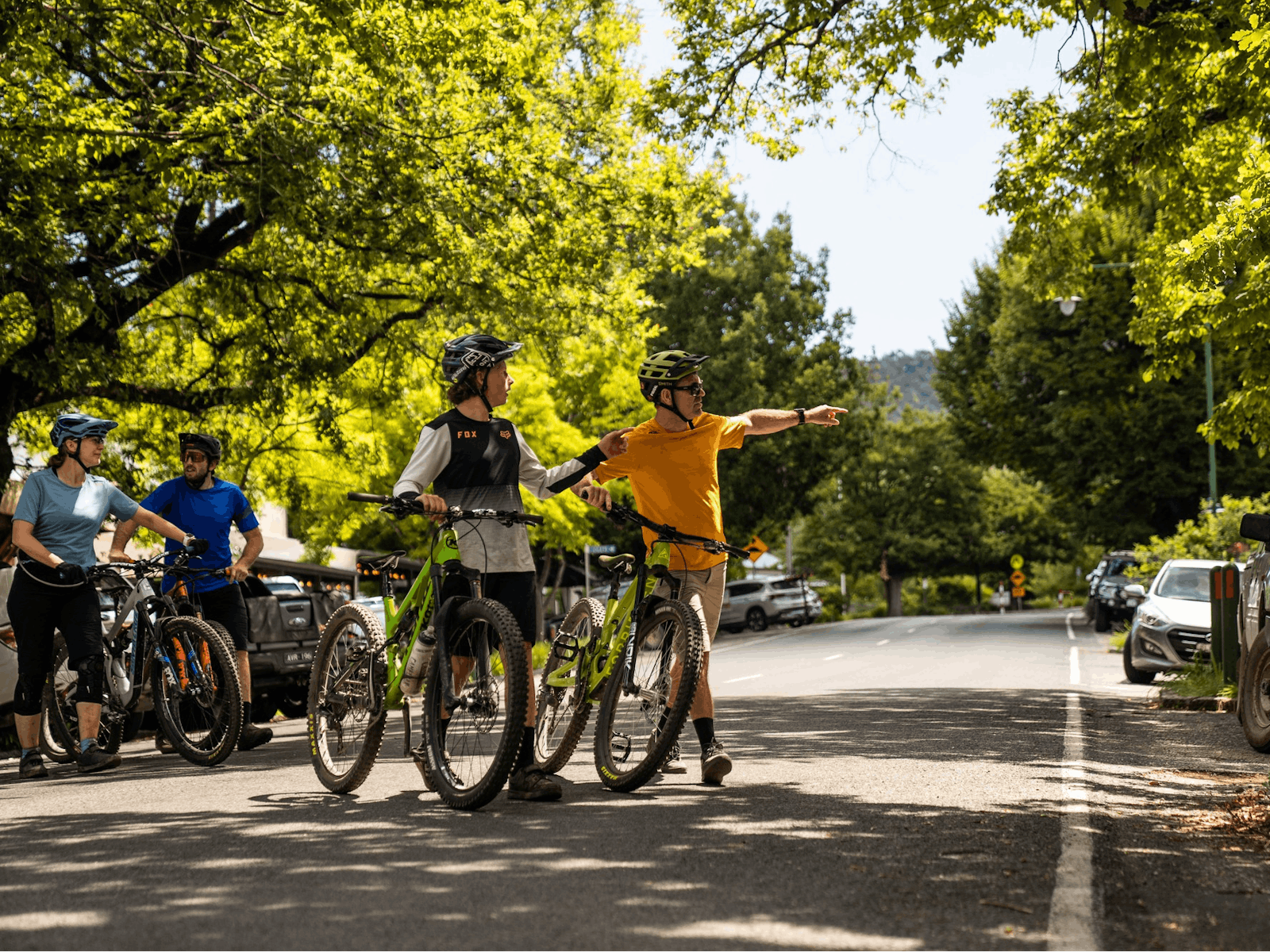 A group of riders wheel their mountain bikes through a historic street scape