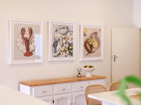 Dining area with framed artwork above a sideboard and a dining table with chairs.