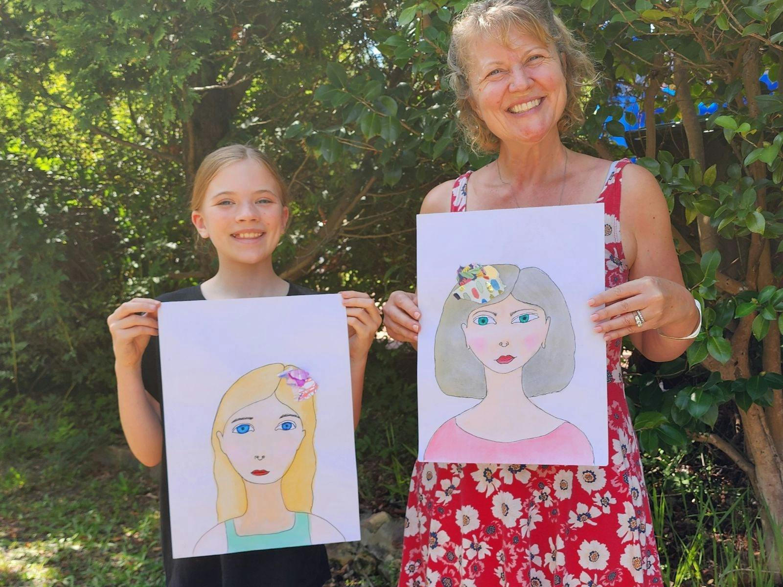 A very happy mother and daughter holding up their artworks after doing the Whimsical Faces class